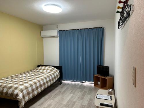 a bedroom with a bed and a television in it at アルピエf 103号室 無料WiFiあります生活しやすい場所です in Kumamoto