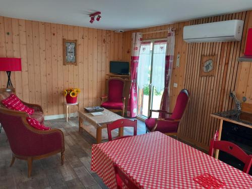 a living room with red chairs and a table and a tv at Le chalet des Patures in Rochefort-Montagne