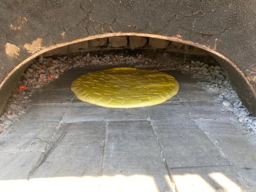 a brick oven with a yellow pizza in it at Camping Lisna in Vau i Dejës
