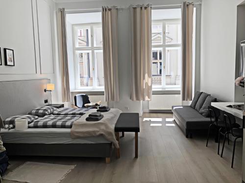 ein Schlafzimmer mit einem Bett, einem Sofa und Fenstern in der Unterkunft Anny 5 Apartamenty in Krakau
