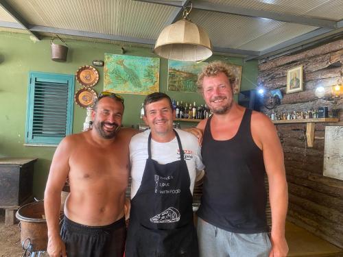three men are posing for a picture in a bar at Camping Lisna in Vau i Dejës