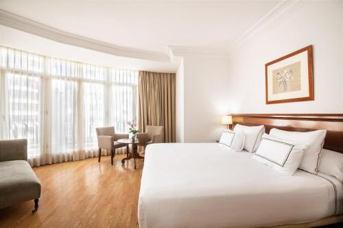 a hotel room with a large bed and a table at Melia Plaza Valencia in Valencia