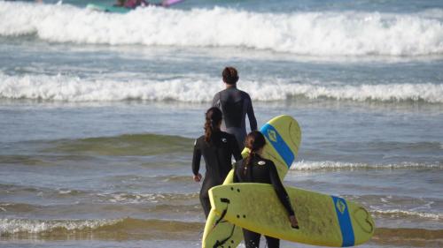 a couple of people standing on the beach with surfboards at CHILL SURFER HOSTEL in Tamraght Ouzdar