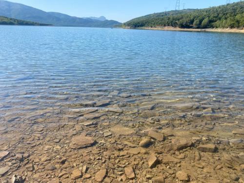 a large body of water with rocks on the shore at Camping Lisna in Vau i Dejës