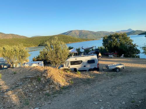 a camper and a truck parked on a hill next to a lake at Camping Lisna in Vau i Dejës