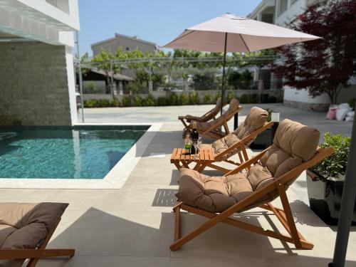two chairs and an umbrella next to a pool at Marini Casa in Ulcinj