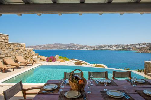 einen Esstisch und Stühle neben einem Pool in der Unterkunft Carpe Diem Villas Mykonos ,Heated Pool! in Ornos