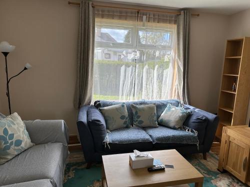 a living room with a blue couch and a window at Lovely Countryside Getaway in Roslin
