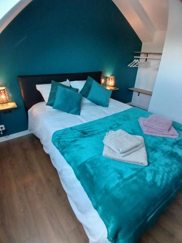 a large bed with blue sheets and blue pillows at Gite avec Spa Le Rubis proche des plages du Débarquement Manche Normandie in Joganville