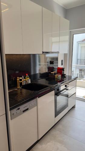 a kitchen with white cabinets and a black counter top at George luxury living in Preveza