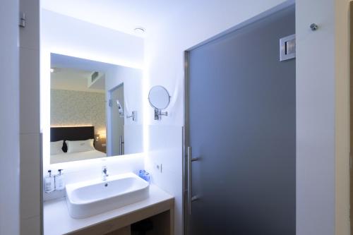 a white bathroom with a sink and a mirror at Hotel Bellariva in Riva del Garda