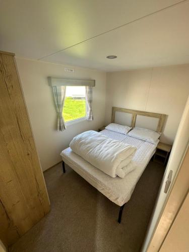 a small bedroom with a bed and a window at Kingfisher 1004 Keyshare holiday lets 8 Berth in Ingoldmells
