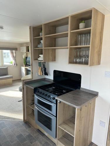 a kitchen with a stove and wooden cabinets at Kingfisher 1004 Keyshare holiday lets 8 Berth in Ingoldmells