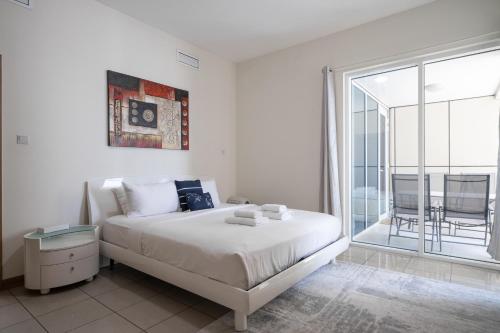 Habitación blanca con cama y balcón. en ALH VAcay - Sulafa Tower - 1 Bedroom, en Dubái