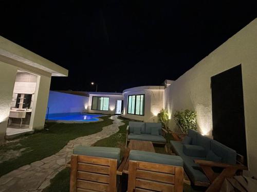 un patio con sillas y una mesa por la noche en HAFAL Resort شاليهات هافال en Riad