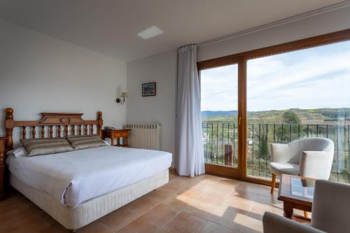 a bedroom with a bed and a balcony with a view at Hotel Conde De Badaran in Badarán