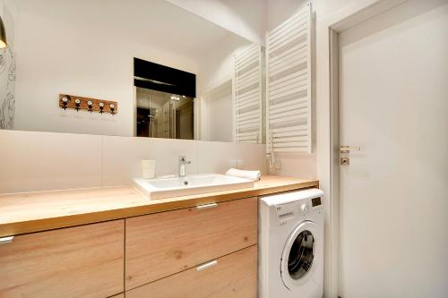 a bathroom with a sink and a washing machine at Apartamenty Apartinfo Szafarnia in Gdańsk