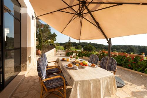 einen Tisch mit Stühlen und einem Sonnenschirm auf einer Terrasse in der Unterkunft Eco Finca Can Alegria with Pool in Llucmajor