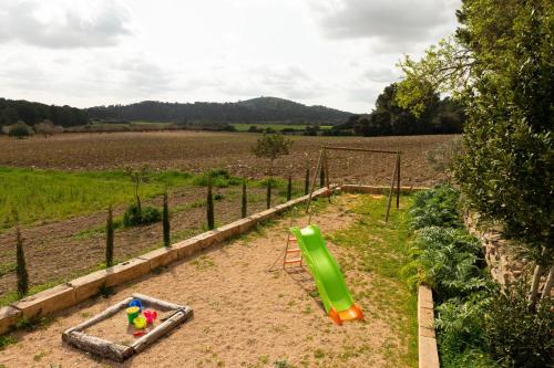 einen Spielplatz mit einer grünen Rutsche auf einem Feld in der Unterkunft Eco Finca Can Alegria with Pool in Llucmajor