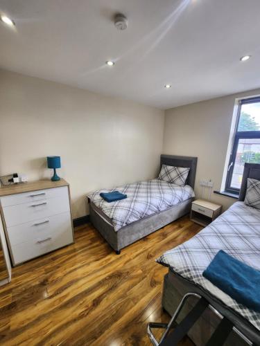 1 dormitorio con 2 camas y suelo de madera en 133 A Park Road en Mánchester
