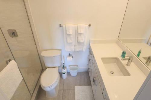 a white bathroom with a toilet and a sink at Sunset Cove - Condo 314 in George Town