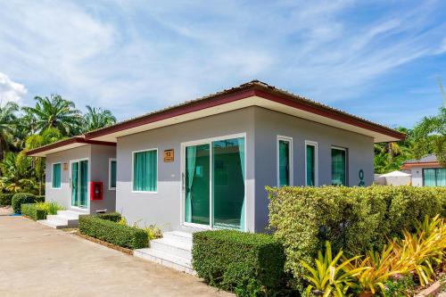 a small white house with green windows and bushes at Neenlawat Riverside in Surat Thani