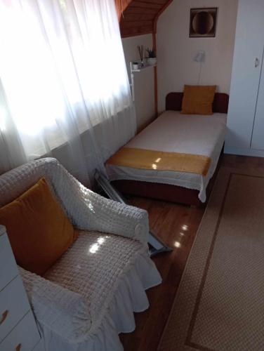 a room with a bed and a couch and a window at Nóra Vendégház in Abádszalók