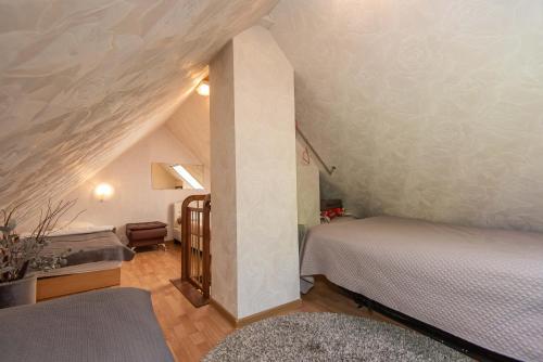 a attic room with two beds and a staircase at Preila Kristima-3 in Preila