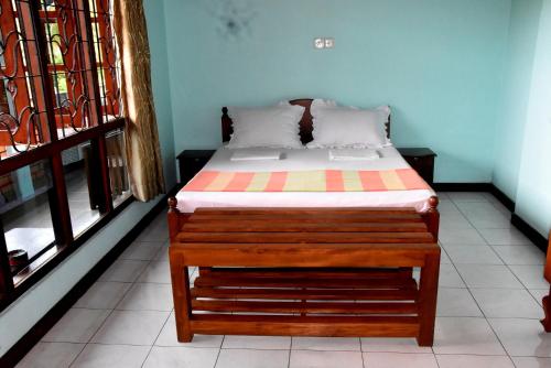 a bed sitting in a room with two windows at Rathna Gems Halt in Ratnapura