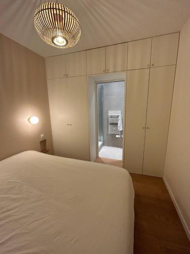 - une chambre avec un lit blanc et un lustre dans l'établissement One bedroom Temple - CityCosy, à Paris