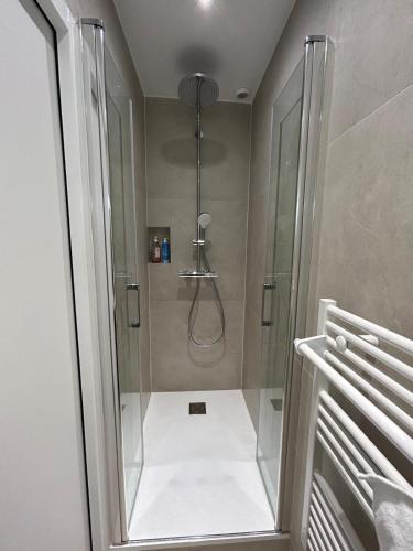 une salle de bain avec une douche avec une porte vitrée dans l'établissement One bedroom Temple - CityCosy, à Paris