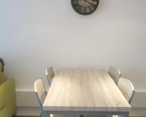 a wooden table with chairs and a clock on the wall at Mini Loft Daval in Paris