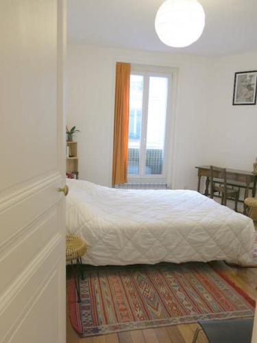 une chambre avec un lit blanc et une fenêtre dans l'établissement Appt Letort CityCosy, à Paris
