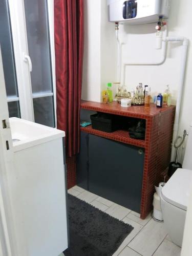 La salle de bains est pourvue de toilettes et d'un rideau de douche rouge. dans l'établissement Charme Belfort CityCosy, à Vincennes