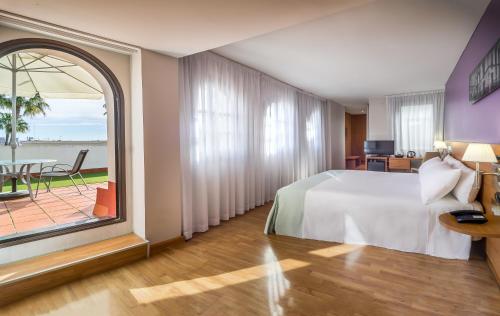 um quarto de hotel com uma cama e uma grande janela em Hotel Jerez Centro em Jerez de la Frontera