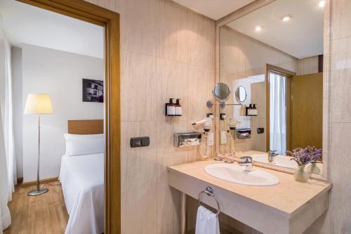baño con lavabo, espejo y cama en Hotel Jerez Centro, en Jerez de la Frontera