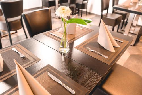 a wooden table with a vase with a flower on it at Remstal Hotel in Weinstadt