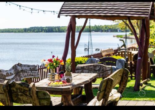 a wooden table with flowers on it next to the water at Preila Kristina-2 in Preila