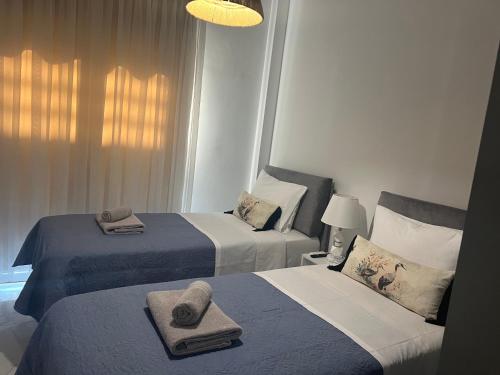 Dos camas en una habitación de hotel con toallas encima. en Athens white apartments, en Atenas