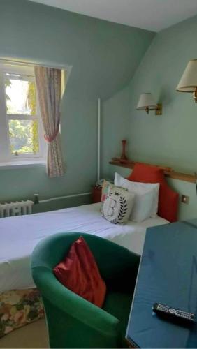 a bedroom with a bed and a green chair at Ballathie House Hotel in Perth