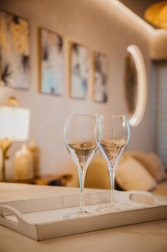 two wine glasses sitting on a tray on a table at Q Coconuts Seaside Suites in Limassol