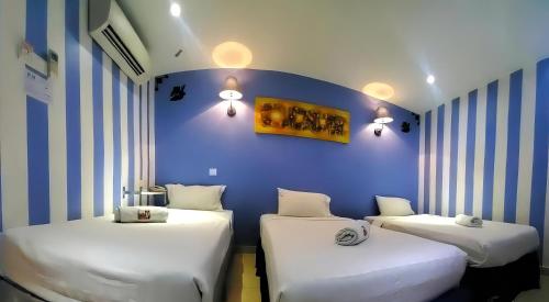 3 camas en una habitación con una pared azul en Boutique Hote123, en Kuala Lumpur