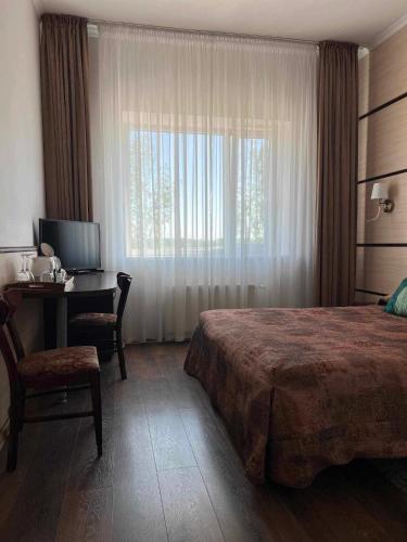 a bedroom with a bed and a desk and a window at Via Baltica in Sargėnai