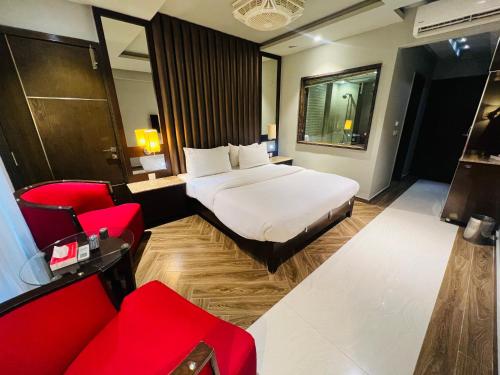 a hotel room with a bed and red chairs at Lahore Continental Hotel in Lahore