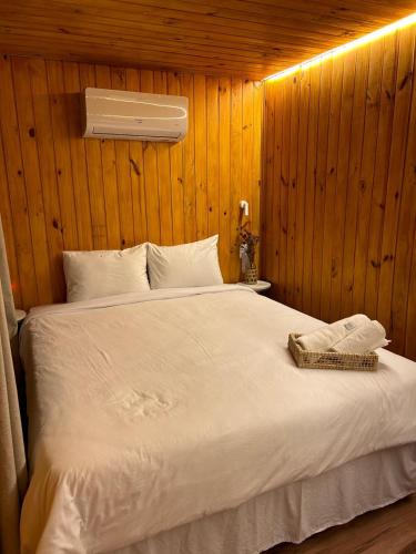 a bedroom with a white bed with a wooden wall at Cabana Natu - Visconde de Mauá in Visconde De Maua