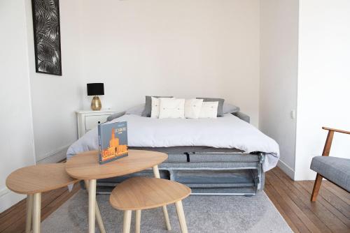 - une chambre avec un lit, une table et deux tabourets dans l'établissement Appartement Perret, au Havre