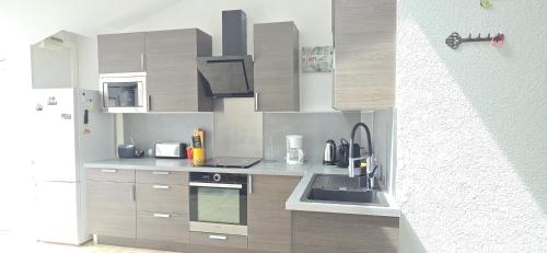 une cuisine avec un évier et un réfrigérateur dans l'établissement La lueur des marées - Appartement lumineux proche de la mer, à Sérignan