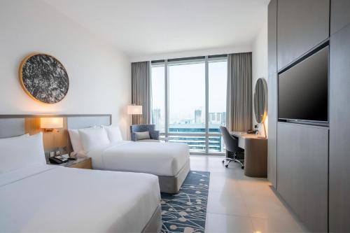 um quarto de hotel com duas camas e uma televisão de ecrã plano em The First Collection at Jumeirah Village Circle, a Tribute Portfolio Hotel no Dubai