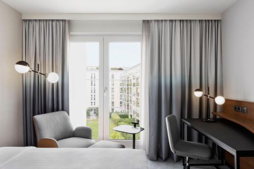 a hotel room with a bed and a desk and a window at Courtyard by Marriott Munich City East in Munich
