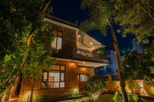 a brick house with a balcony at night at Hostie Vaikuntha - 3BHK Mountain Villa, Dehradoon in Dehradun